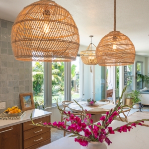 Woven dome pendants over quartz island with bright pink florals, dining nook, and floor-to-ceiling windows