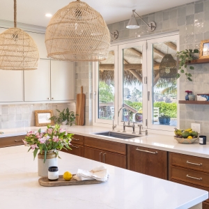 Expanded kitchen window with three sconces over Rohl undermount sink and Kohler Edalyn bridge faucet, open walnut shelves, and Marin tile