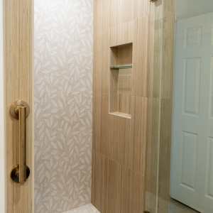 Shibusa porcelain shower with pebble mosaic floor and brass grab bar