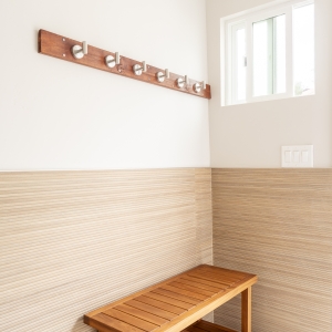Wood bench and robe hooks over Porcelanosa wainscot