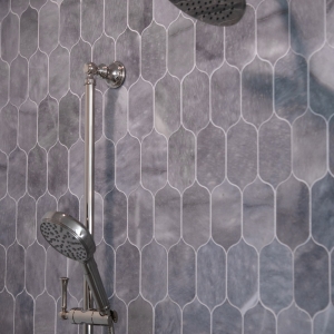 Chrome rain shower head and handheld sprayer on blue-gray lotus tile shower wall