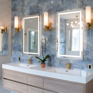 Full view of a modern double vanity with oak cabinetry and a blue onyx-look tile wall