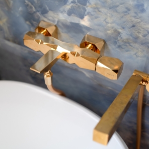 Brass tub filler and handheld sprayer mounted against a blue onyx-look tile wall