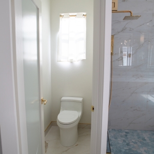 Blue hex mosaic shower floor with a brass curb edge beside a glass panel