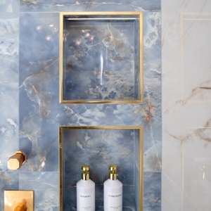 Custom shower niches in blue onyx-look tile with brass trim accents