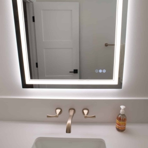 Wall-mounted bath faucet with illuminated mirror and white Silestone countertop