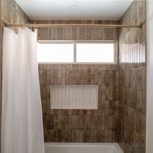Bathtub and shower with glossy brown porcelain tile and white niche