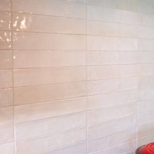 Glossy white Celine porcelain backsplash tile behind the induction cooktop