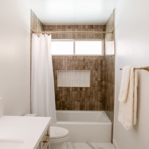 Hall bathroom remodel with brown gloss shower tile and white niche