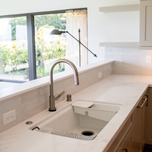 Kitchen sink and Delta pull-down faucet with bright countertop and backsplash