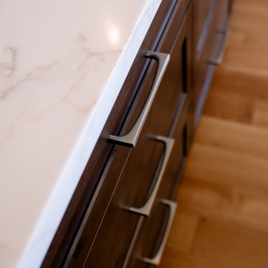 Close-up of stained knotty alder island drawers with brushed metal pulls
