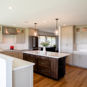 Open kitchen with dark alder island, oatmeal cabinets, and white countertops