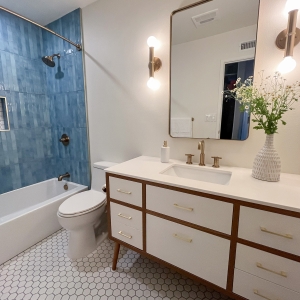 Hall bathroom with blue tile, white tub, and mid-century vanity