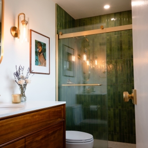 Primary bathroom with walnut vanity and green tiled shower